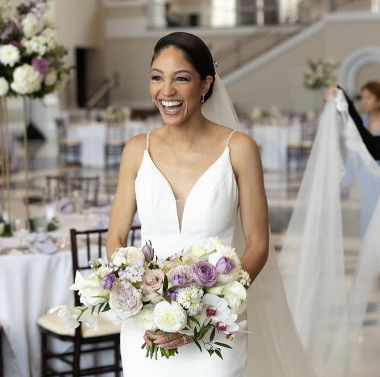 Radiant joyful bride in grand ballroom with purple and blush bouquet